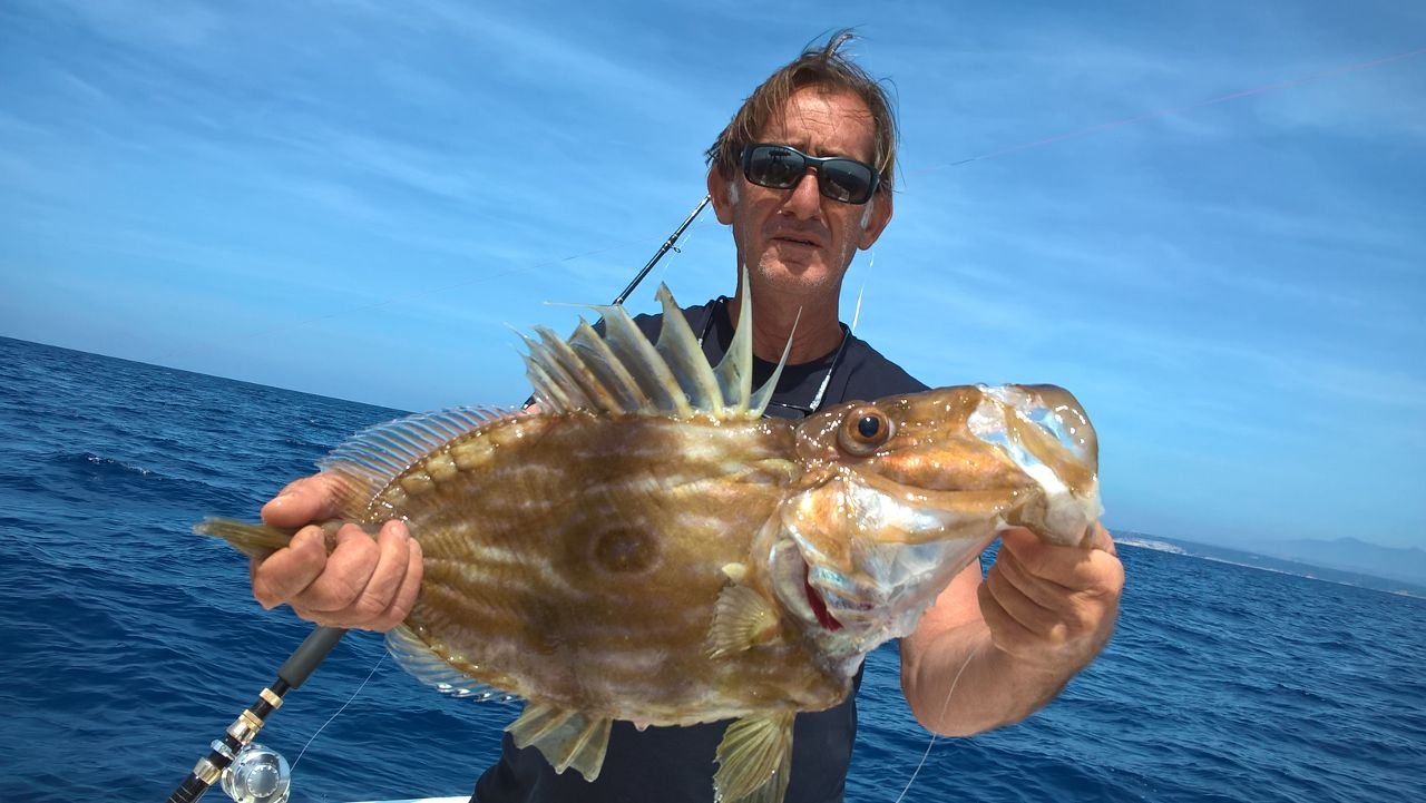Massimo Deiana mostra un san pietro appena pescato durante un'uscita di pesca a Santa Teresa, Sardegna