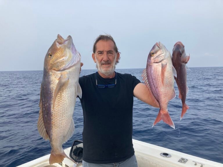 Massimo Deiana, guida di pesca federale, con due pesci catturati durante un'uscita di pesca a Santa Teresa, Sardegna