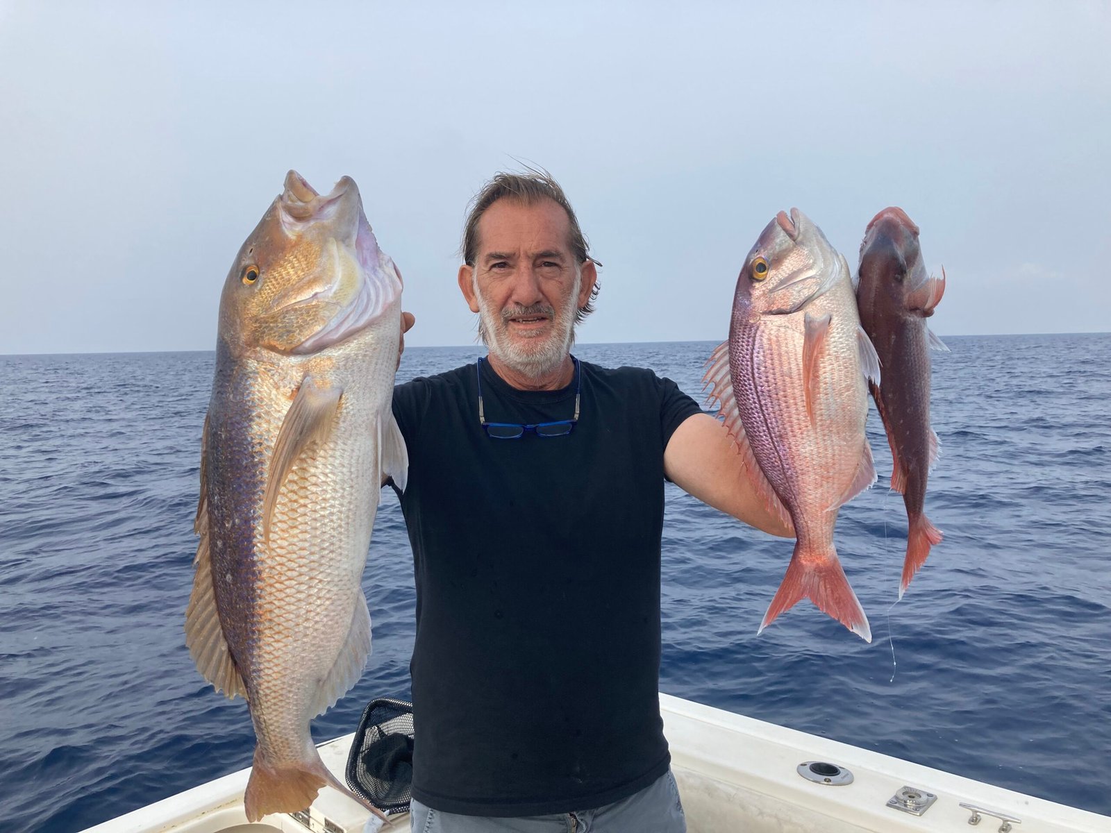 Massimo Deiana, guida di pesca federale, con due pesci catturati durante un'uscita di pesca a Santa Teresa, Sardegna